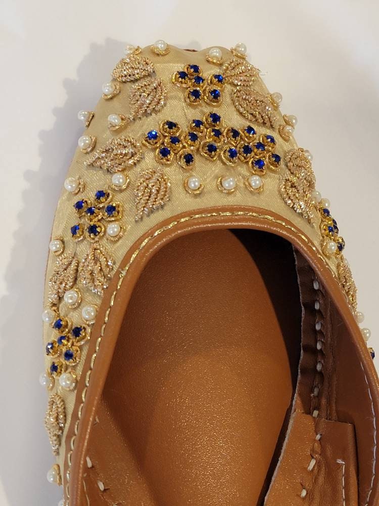 Gold base khussa with white pearls and blue diamonds and kora dabka work.