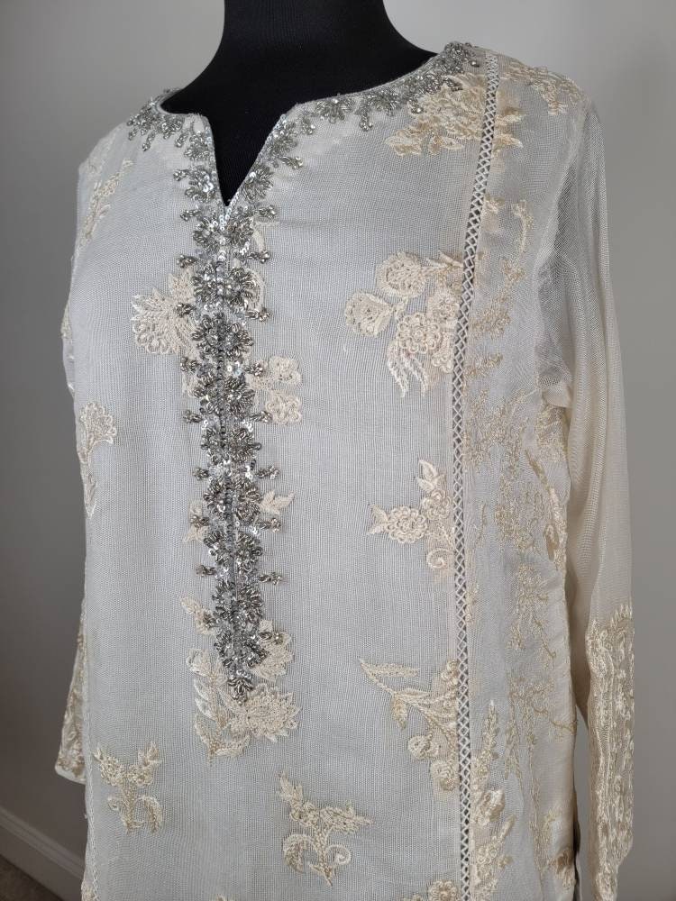 Gorgeous white cotton net shirt with handwork on gala. Pant and duppata included. Pakistani ready to wear formal attire. Agha noor.